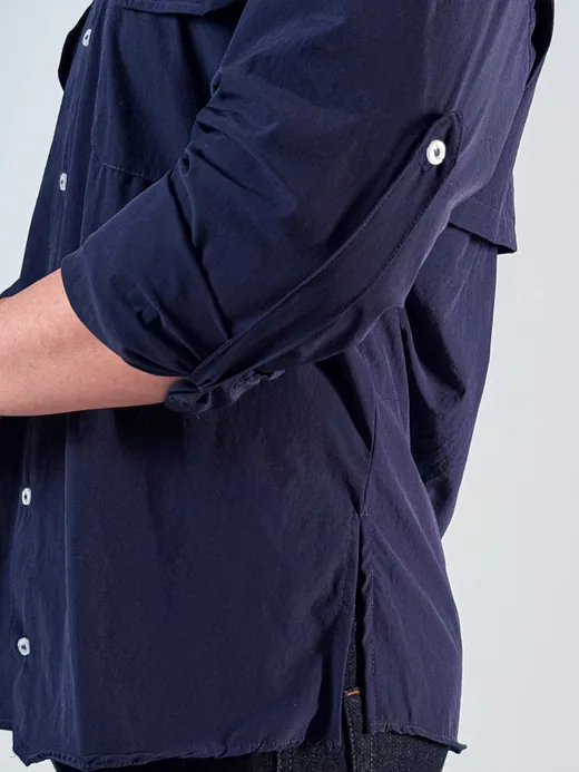 Camisa azul marinho com a manga arregaçada e presa, virando manga curta.