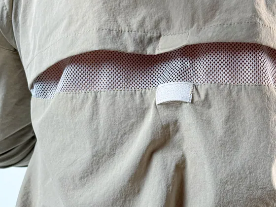 Macro do painel de ventilação em tela, nas costas da camisa areia.